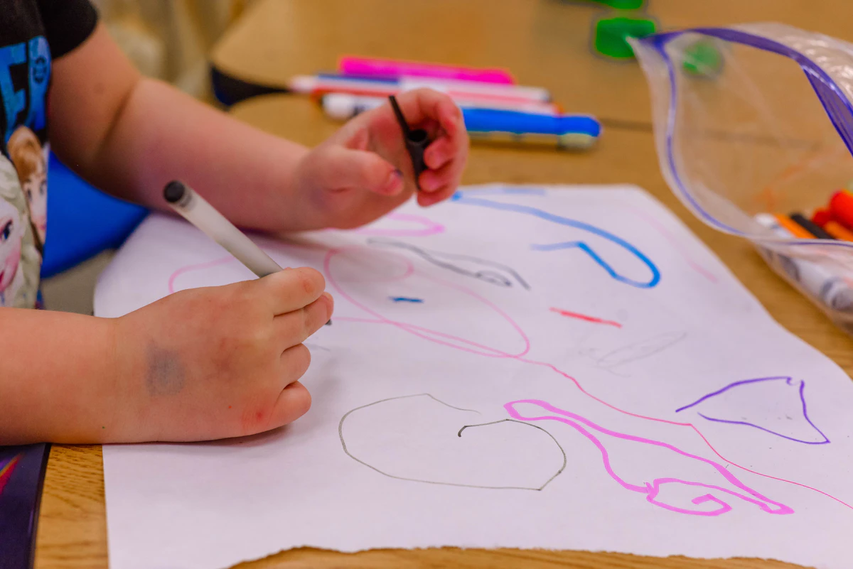 Kinderhanden tekenen met stiften aan tafel